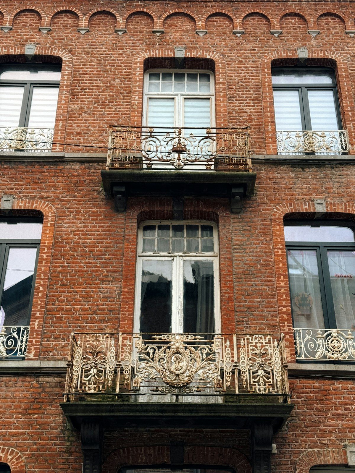 Façade en brique et balcons en ferronnerie d'une maison de maître bruxelloise